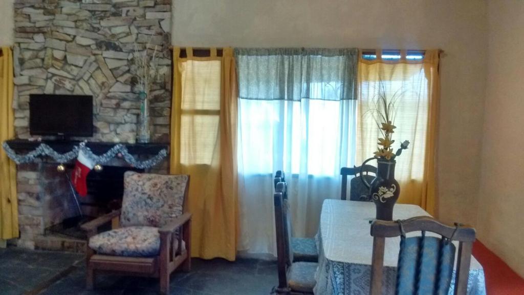 sala de estar con chimenea, mesa y sillas en Finca La Casa Amarilla en San Rafael