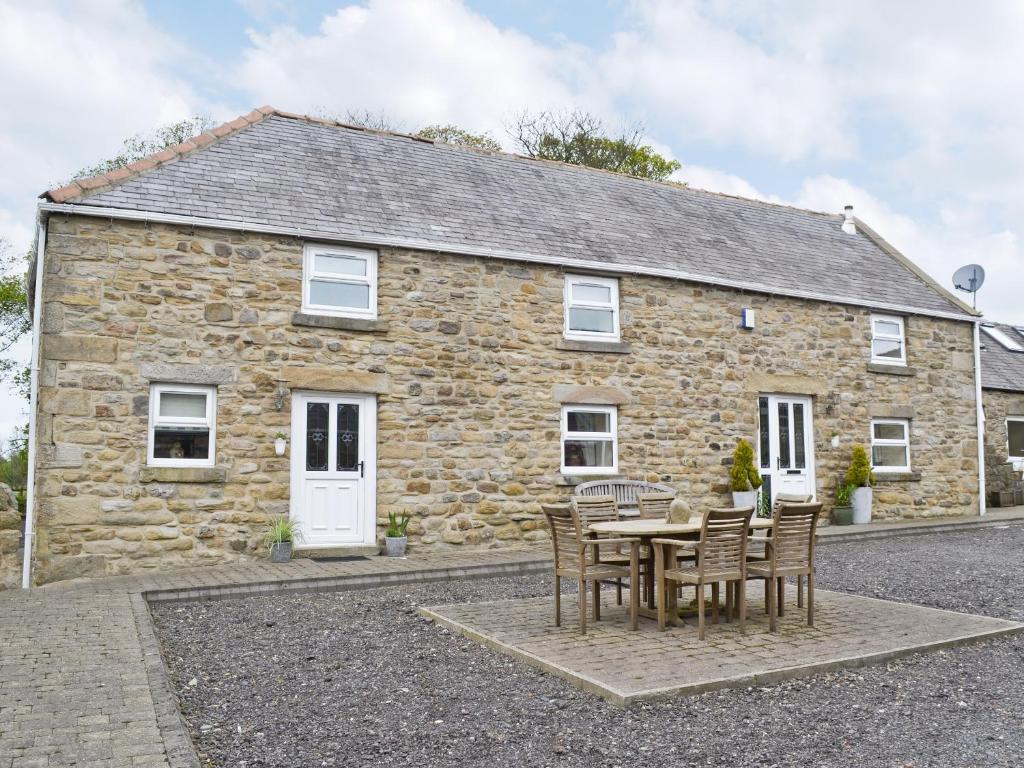 a stone house with a table and chairs in front of it at John Wesley Cottage in Tantobie