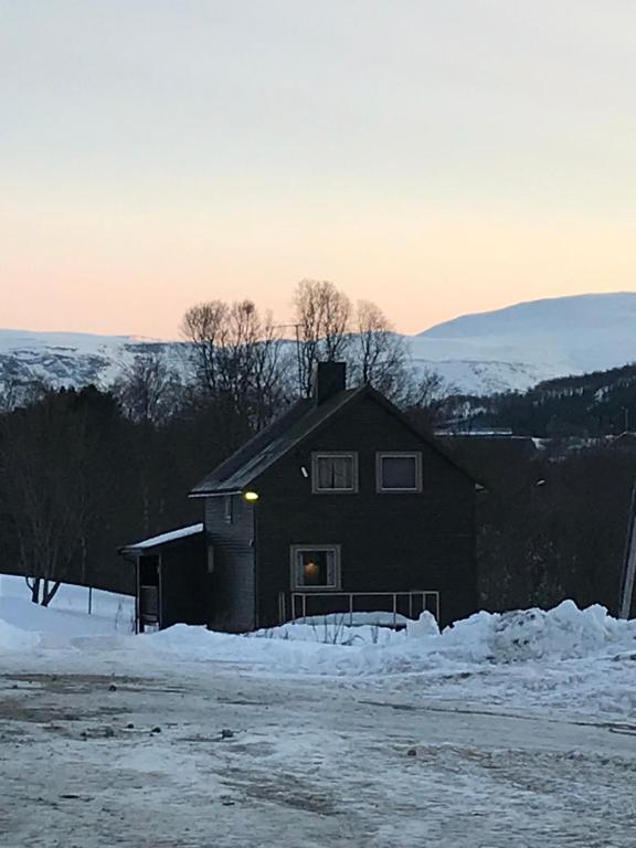 a black house with snow on the ground at Kjelkebakken Gard in Lyngseidet