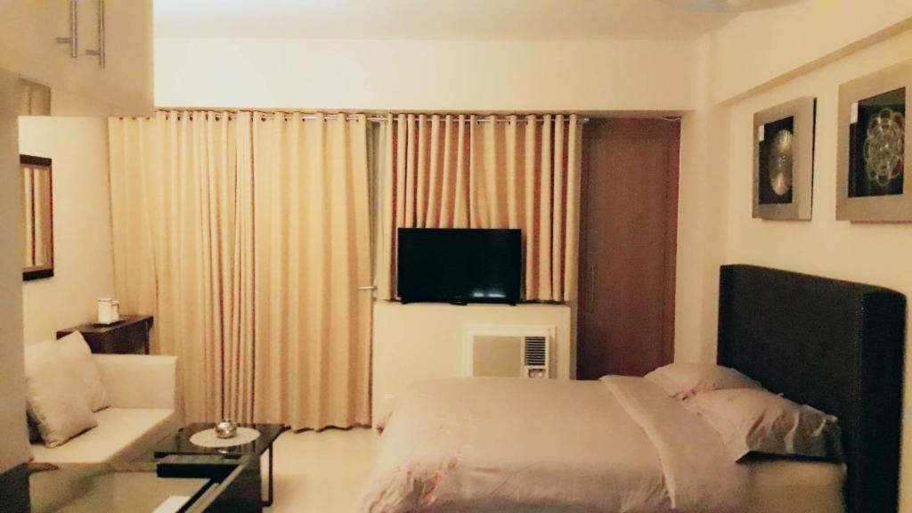 sypialnia z łóżkiem, kanapą i telewizorem w obiekcie Palm Tree Villas 1 w mieście Manila