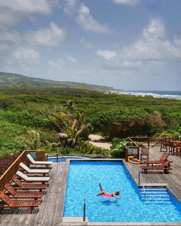 a person swimming in a swimming pool with a beach at Santosha Barbados in Saint Andrew