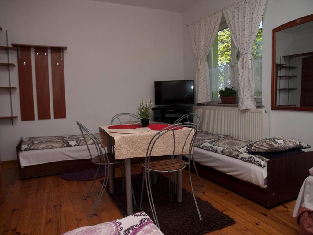 ラシンにあるPokoje Gościnne "Amelia"のベッド2台、テーブル、椅子が備わる客室です。