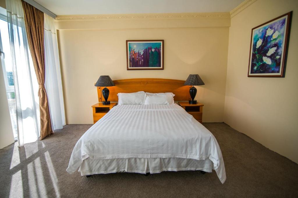 a bedroom with a large white bed with two lamps at Hotel Feni in Kavadarci