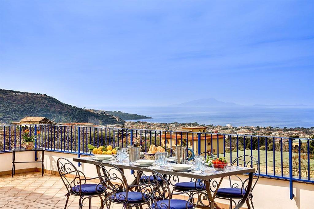 een tafel en stoelen op een balkon met uitzicht op de oceaan bij Elena Apartment in Piano di Sorrento
