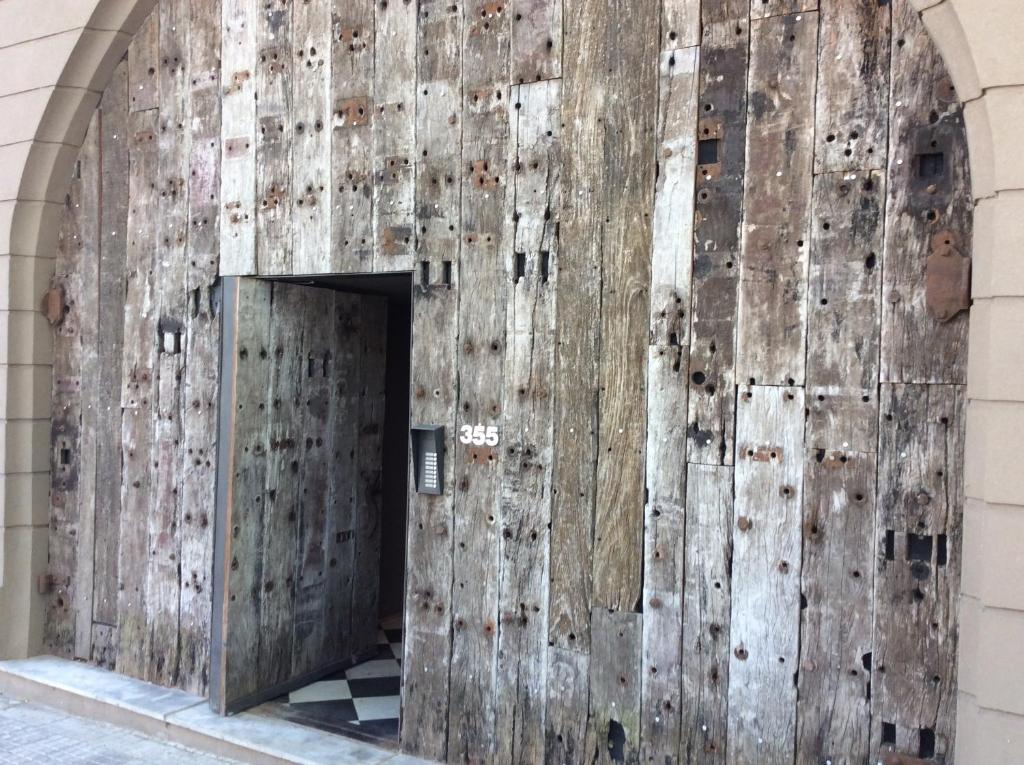 una antigua puerta de madera en el lateral de un edificio en Las Glicinas Boutique Apartments en Colonia del Sacramento