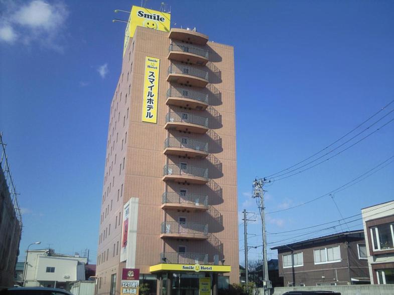 ein hohes Gebäude mit einem gelben Schild darüber in der Unterkunft Smile Hotel Towada in Towada