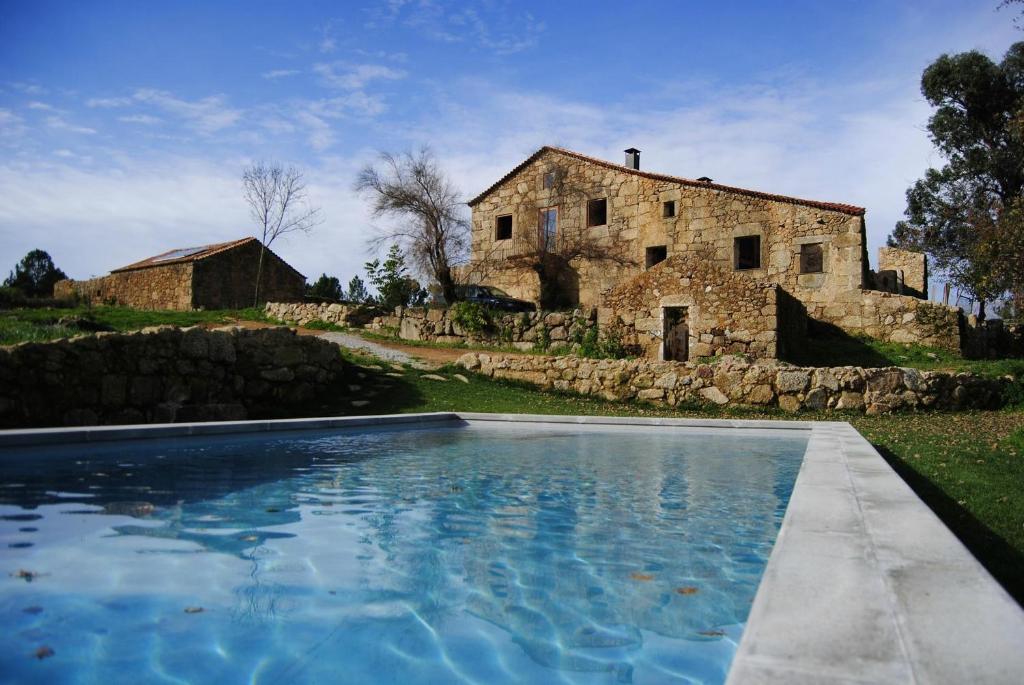 una antigua casa de piedra con una piscina frente a ella en Quinta de Seves en Covilhã