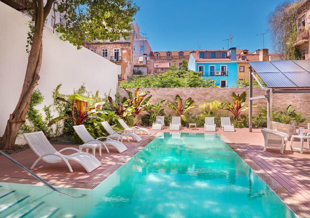 a swimming pool with white chairs and a house at Hapimag Apartments Lisbon in Lisbon