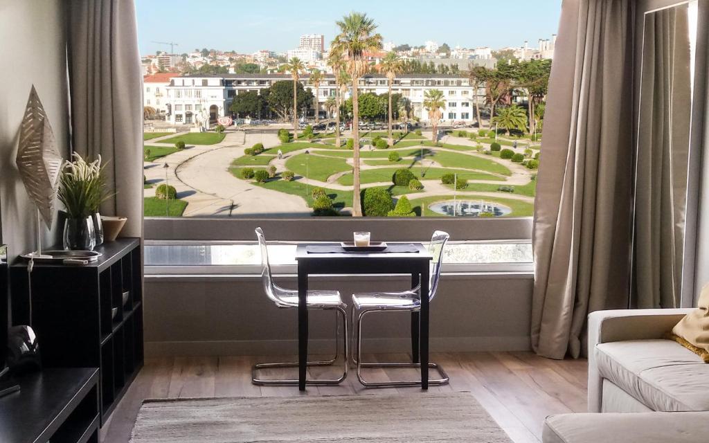 Habitación con mesa, sillas y ventana grande. en BEACHFRONT Cascais,Estoril Apartment, en Estoril