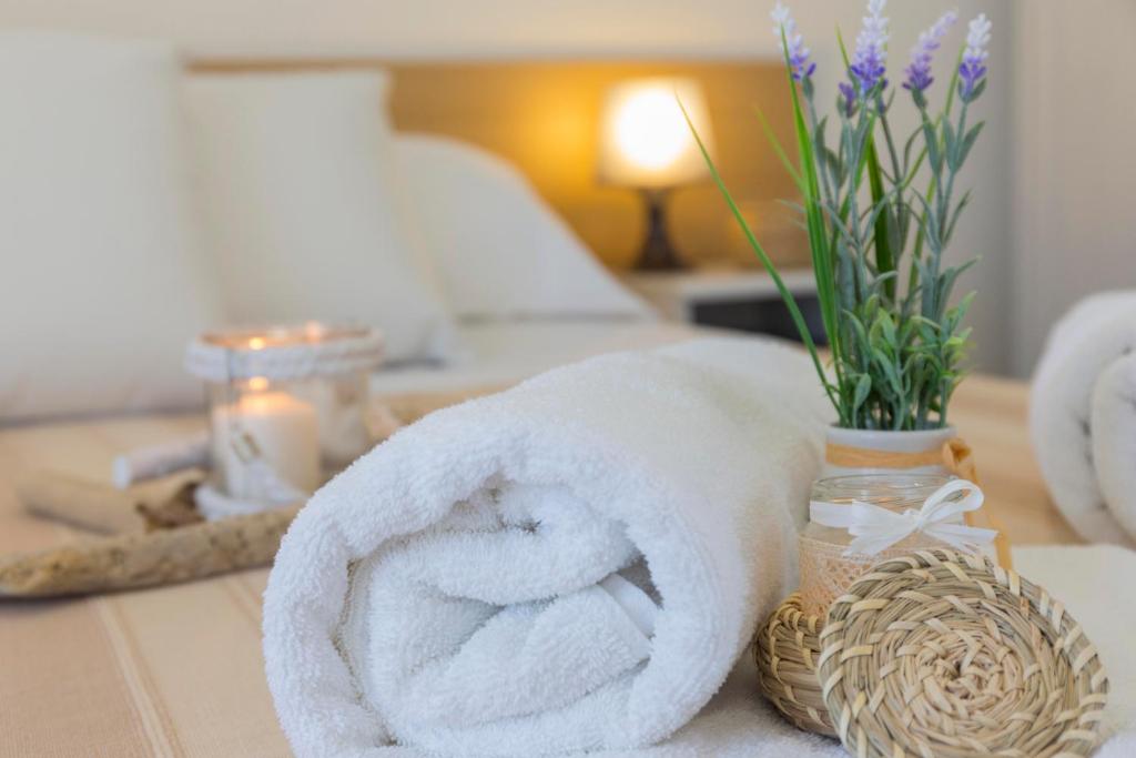 a towel and a vase with flowers on a table at Mareinsicilia Cannamara Appartamenti in Donnalucata