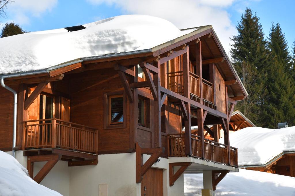 uma casa de madeira com neve no telhado em Chalet Orlando em Les Gets