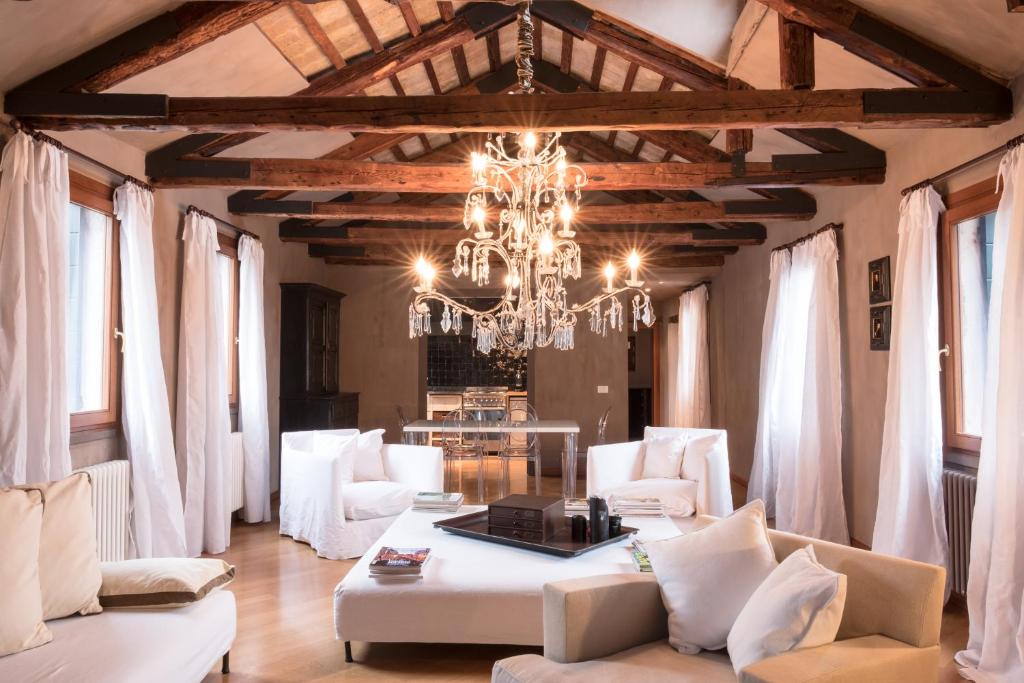 un soggiorno con mobili bianchi e lampadario pendente di Ca' Navagero Apartments a Venezia