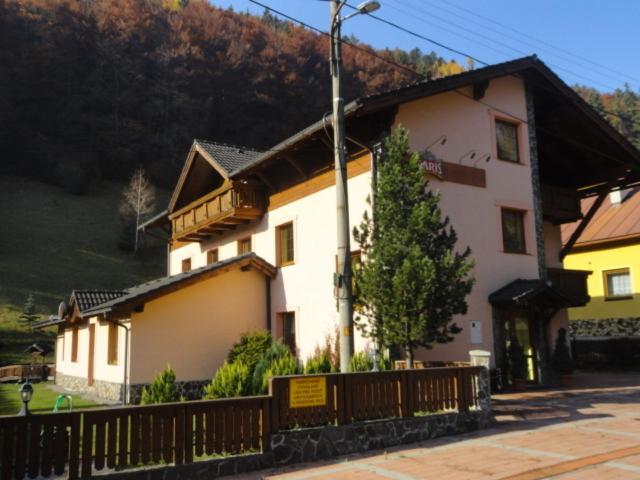 uma grande casa branca com uma cerca de madeira em frente em Penzion Eka em Brezno