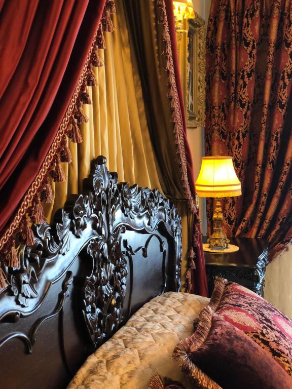 a bedroom with a bed with red curtains and a lamp at Grand Duke Apartments in Vilnius