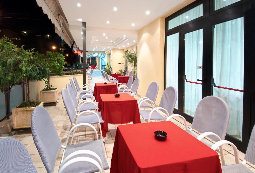 a row of tables and white chairs with red table cloth at Hotel Villa Lieta in Rimini