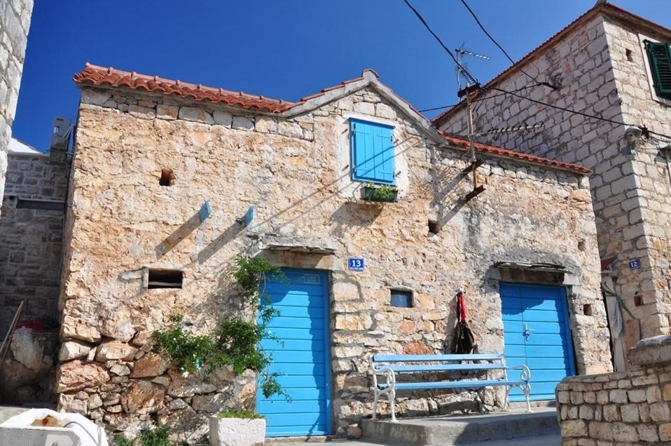 un edificio de piedra con dos puertas de garaje azules en Vacation House Sara&Noa, en Maslinica