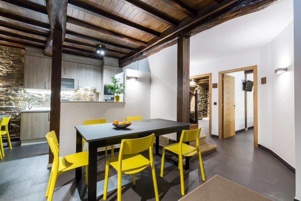 a dining room with a black table and yellow chairs at Albergue O Candil in Melide