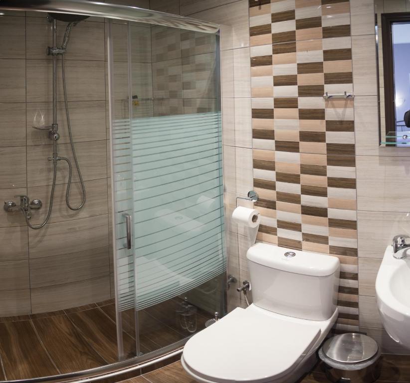 a bathroom with a toilet and a glass shower at Galazio Limani - Rooms to let in Moúdhros