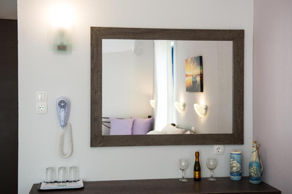 a mirror on a wall above a table with wine glasses at Galazio Limani - Rooms to let in Moúdhros