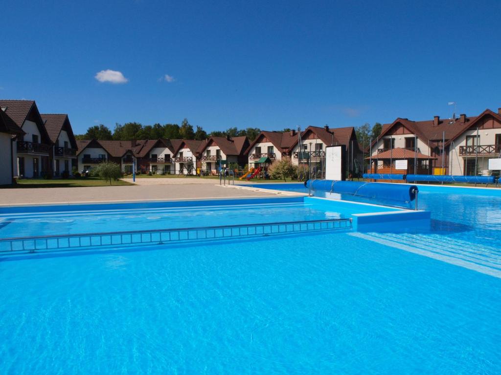 a large blue swimming pool with houses in the background at Apartament Makowe Pola in Żarnowska