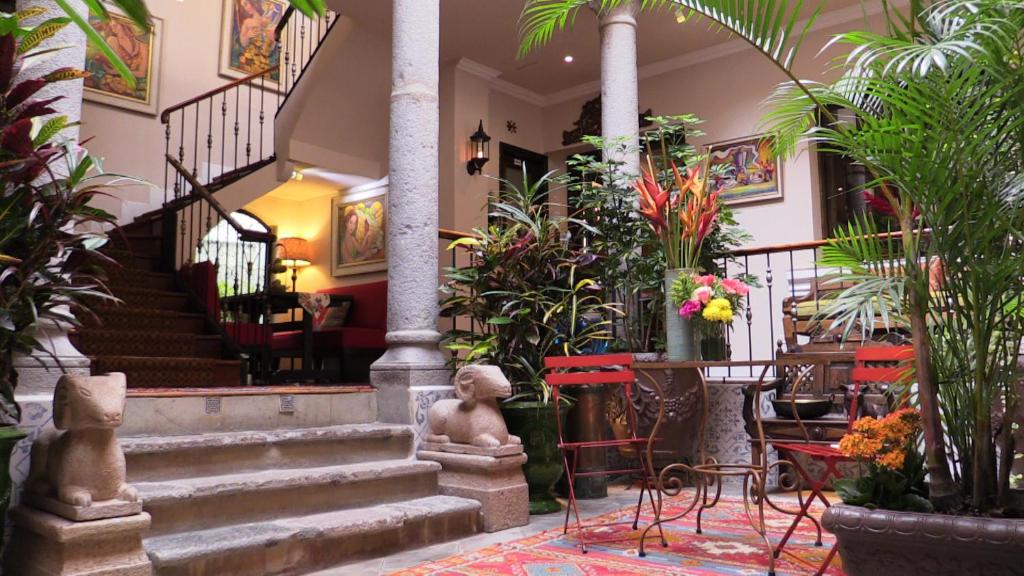 a lobby with stairs and tables and plants at Villa Colonna in Quito