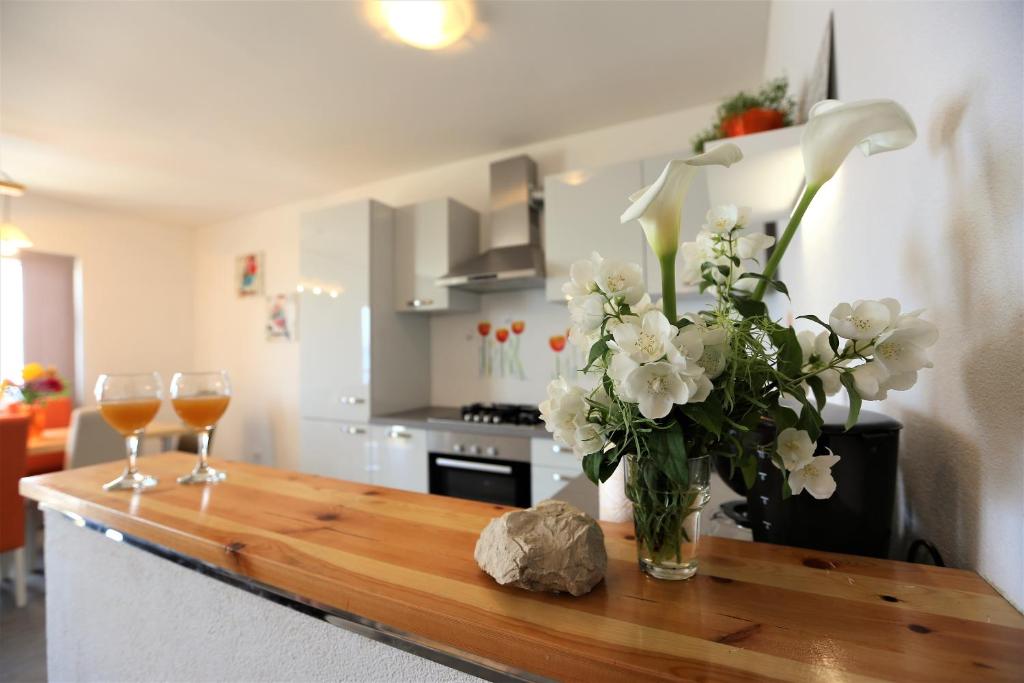una mesa con un jarrón de flores y dos copas de vino en Apartments Ivka, en Omiš