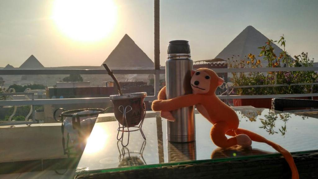 a toy monkey sitting on a table with pyramids in the background at Horus Guest House Pyramids View in Cairo