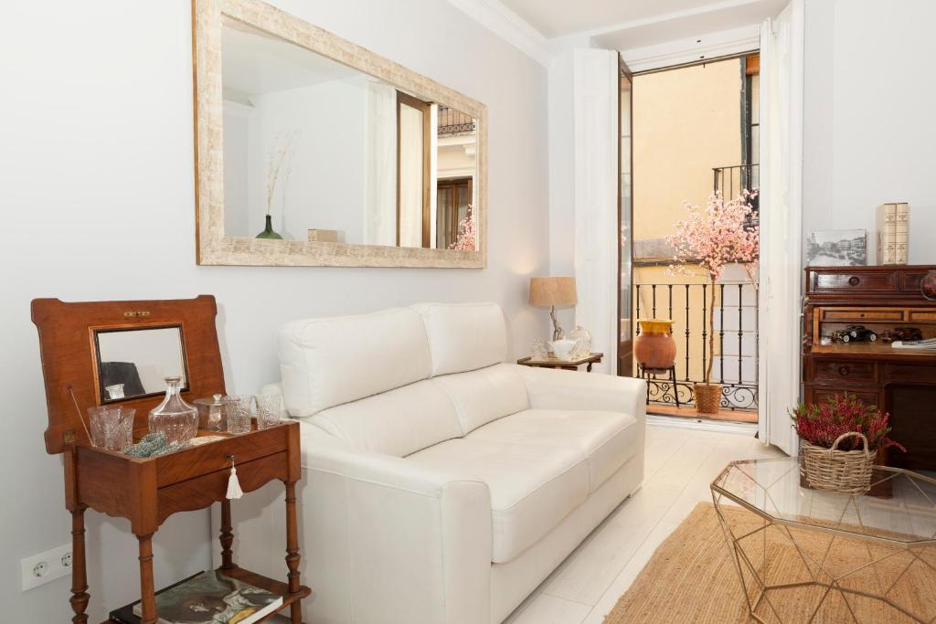 ein Wohnzimmer mit einem weißen Sofa und einem Spiegel in der Unterkunft Elegante y espacioso, junto a la Plaza Mayor in Madrid