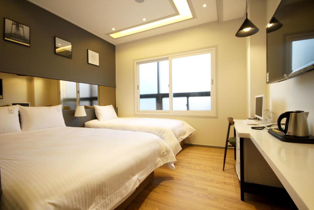 een hotelkamer met 2 bedden en een raam bij If Business Hotel in Changwon