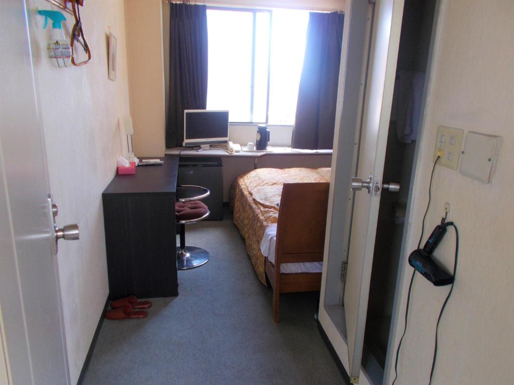 a room with a bed and a desk with a computer at Hotel Avanti in Tokushima