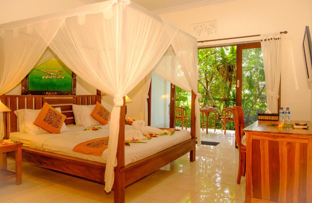 a bedroom with a canopy bed and a television at Semujan Bungalow in Ubud