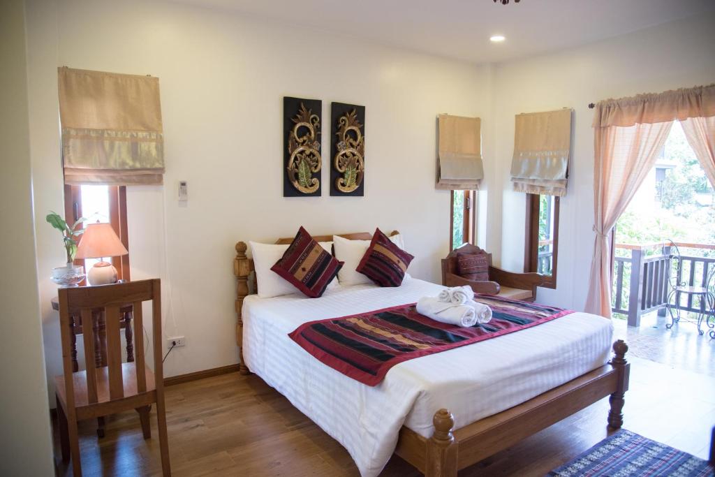 1 dormitorio con 1 cama con sábanas blancas y ventanas en Gordnuea Boutique House- SHA Extra Plus, en Chiang Mai
