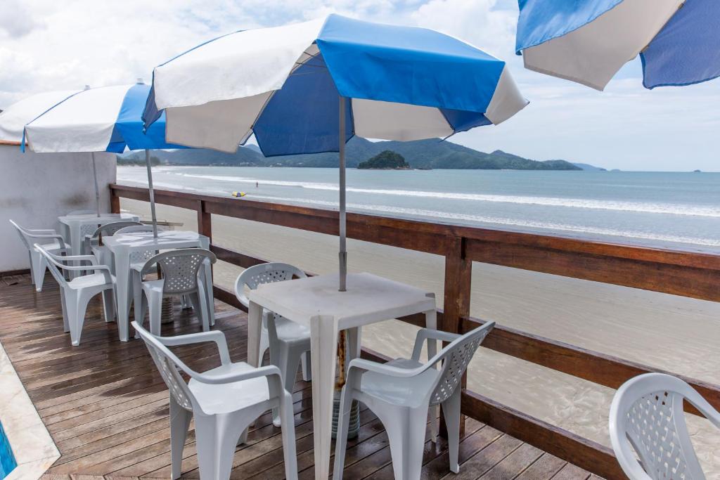 uma fila de mesas e cadeiras com guarda-sóis num deque em Pousada Mar Virado em Ubatuba