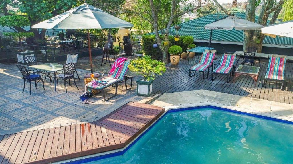 a swimming pool with a table and chairs and an umbrella at Elizabeth Manor Guest House in Johannesburg