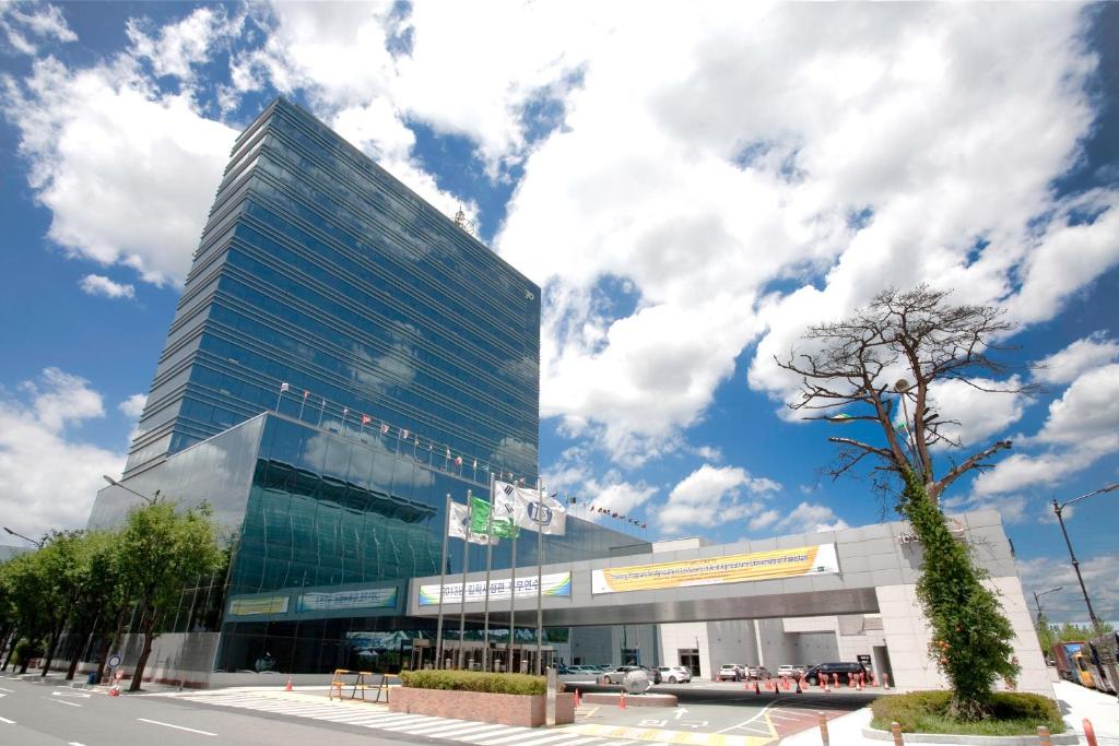 a tall glass building in front of a street at Hotel Interburgo Exco in Daegu