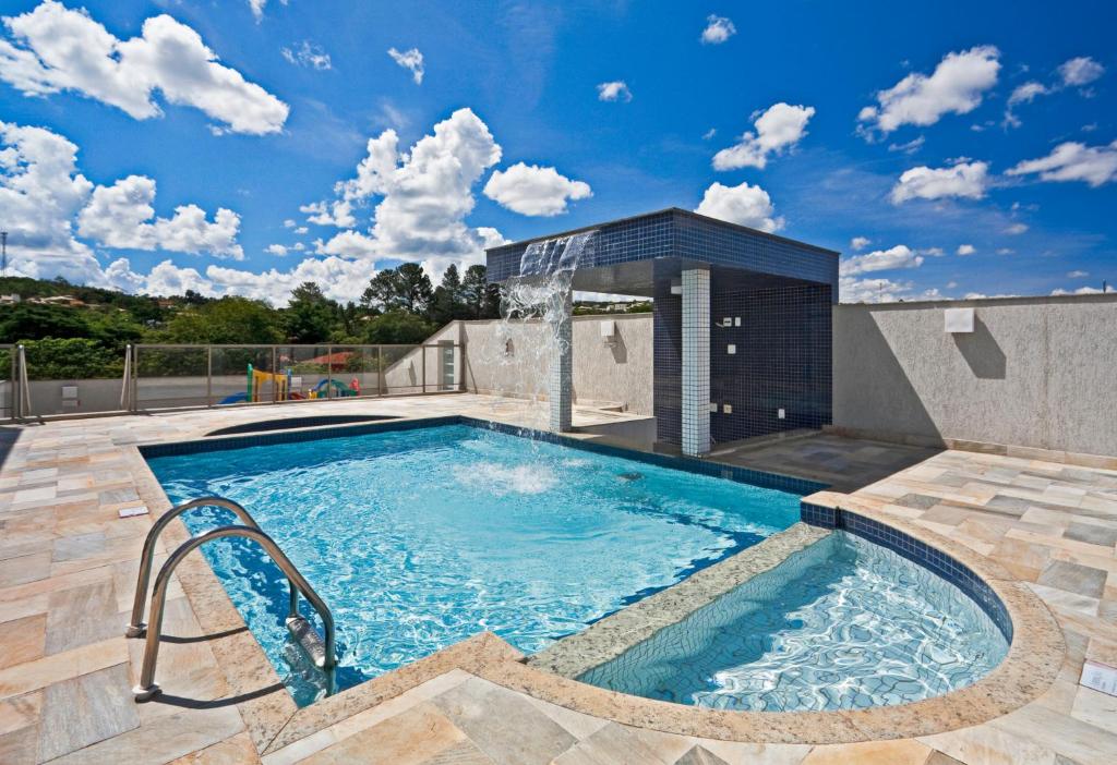 uma piscina com uma fonte num edifício em Ramada Hotel & Suites Lagoa Santa By Wyndham em Lagoa Santa