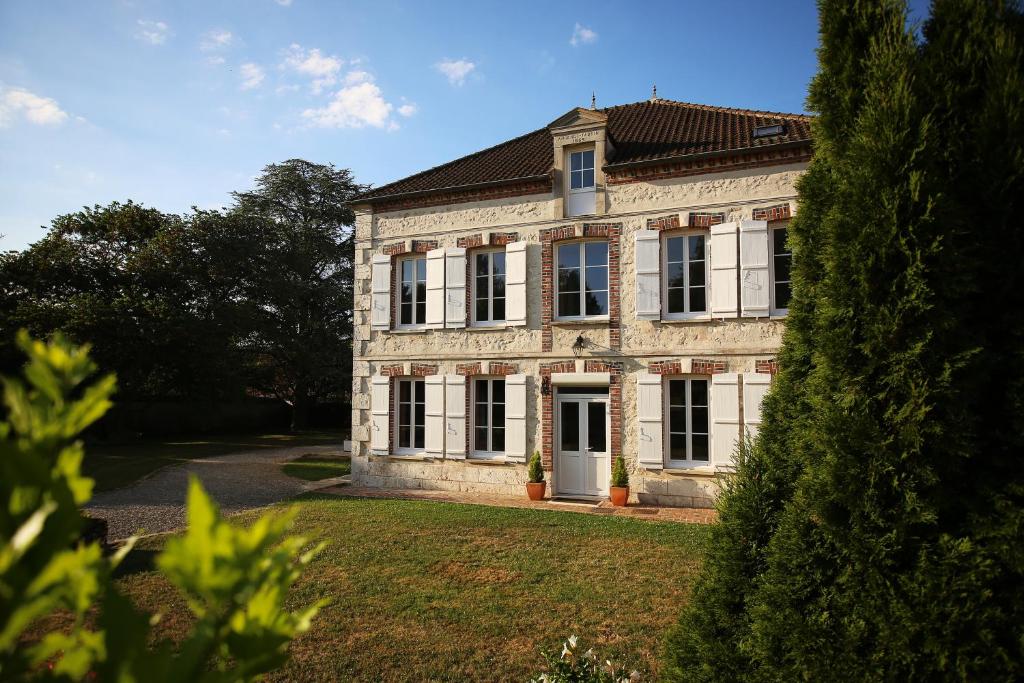 une grande maison en briques blanches avec une cour dans l'établissement Les Rêves de Flamboin, à Gouaix