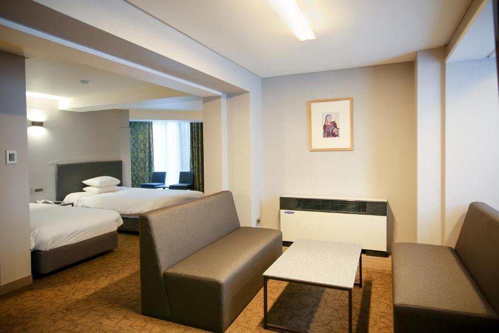 a hotel room with two beds and a couch at Savoy Hotel Myeongdong in Seoul