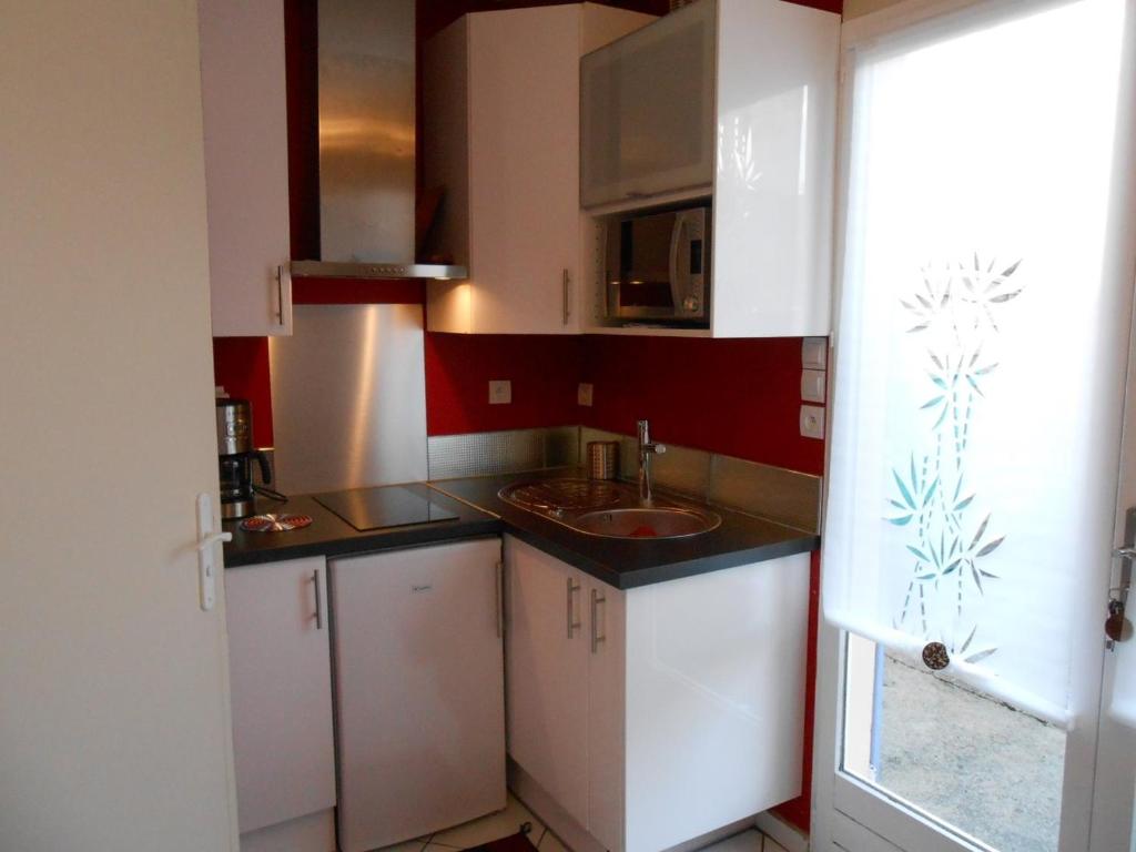 a small kitchen with white cabinets and a sink at Gite C in Sotteville-lès-Rouen