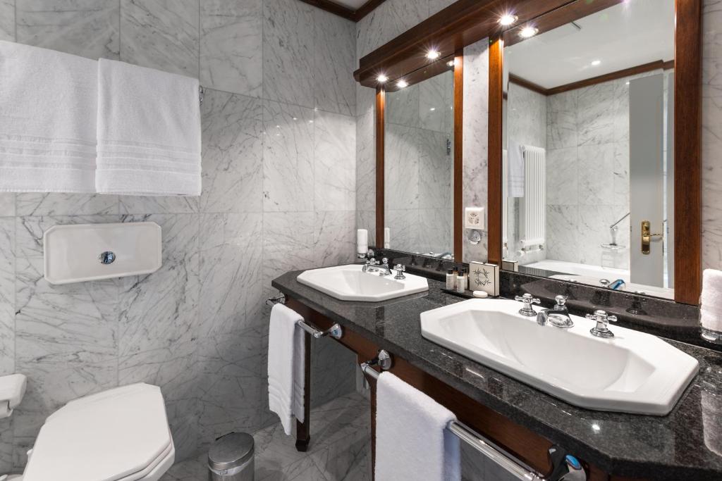 a bathroom with two sinks and a large mirror at Château Gütsch in Luzern