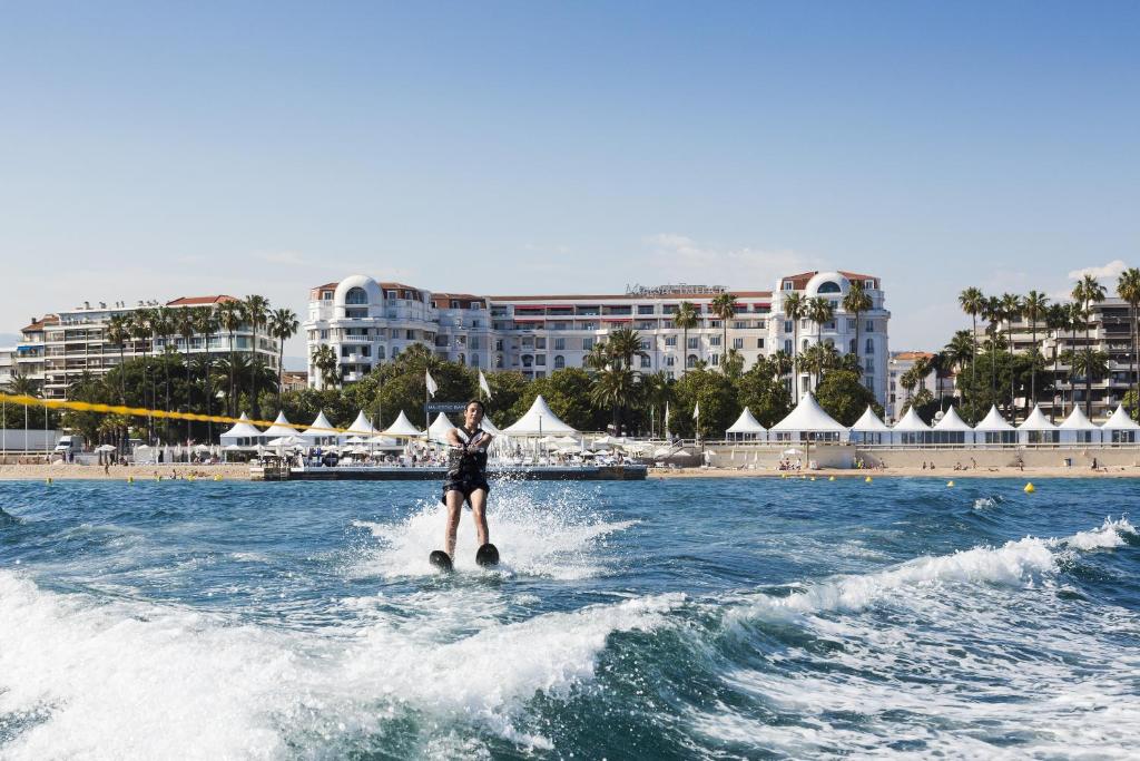 a person water skiing in the water near a beach at Hôtel Barrière Le Majestic Cannes in Cannes
