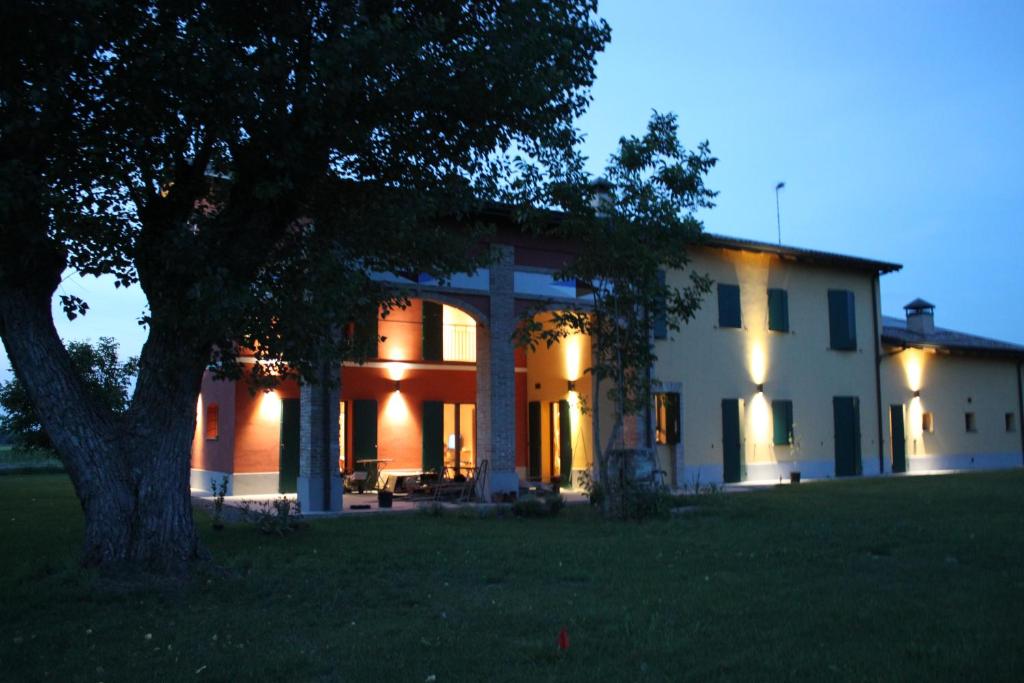 ein großes weißes Haus mit einem Baum davor in der Unterkunft La casa dei gatti in Soragna