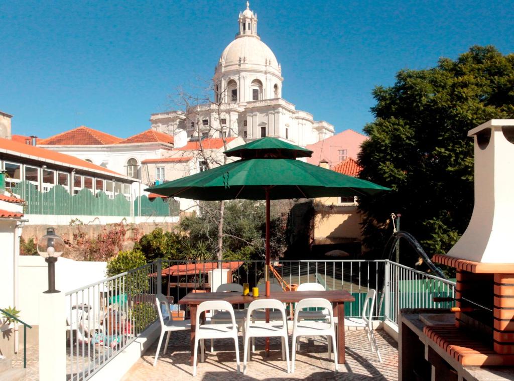 un tavolo e sedie con ombrellone verde sul balcone di Alfama Terrace a Lisbona