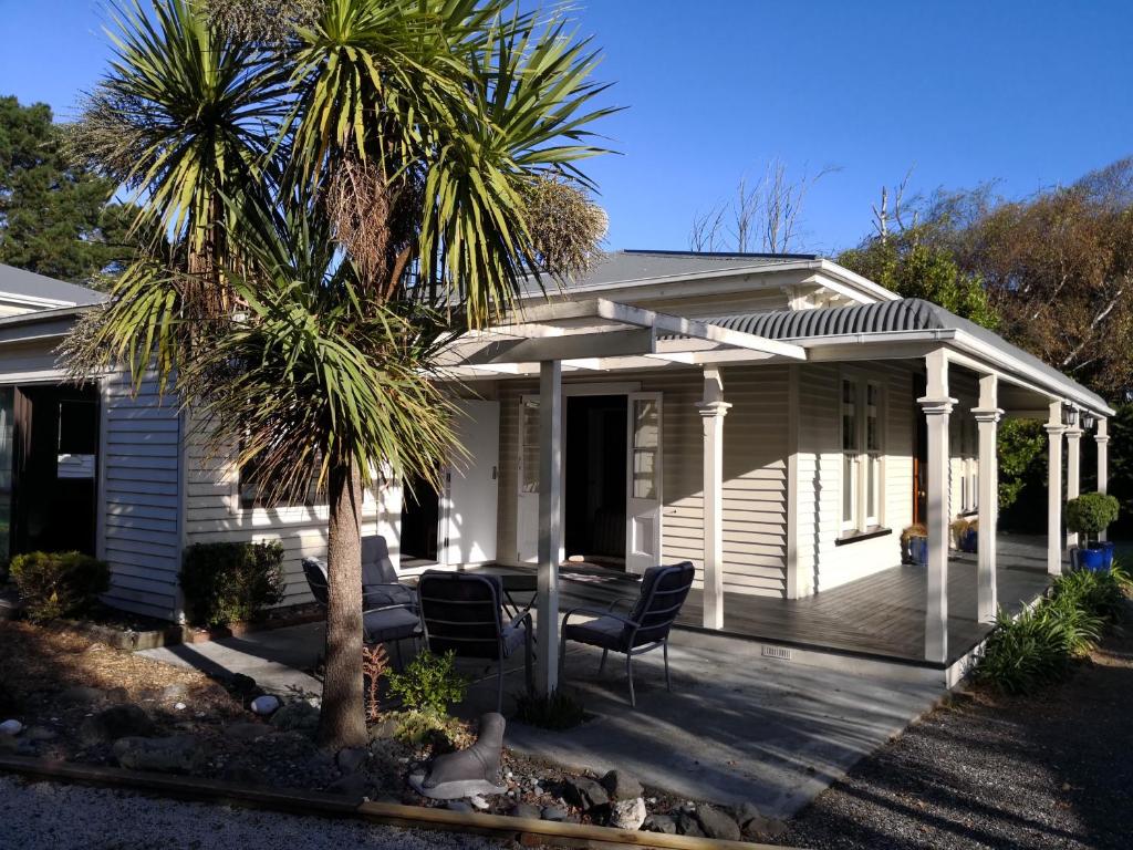 凱庫拉的住宿－漂流木度假屋，一个带门廊、椅子和棕榈树的房子