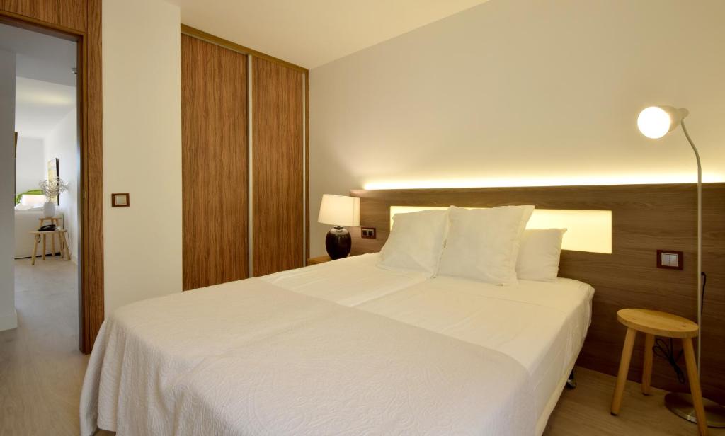 a bedroom with a large white bed and a lamp at Pula Golf Resort in Son Servera