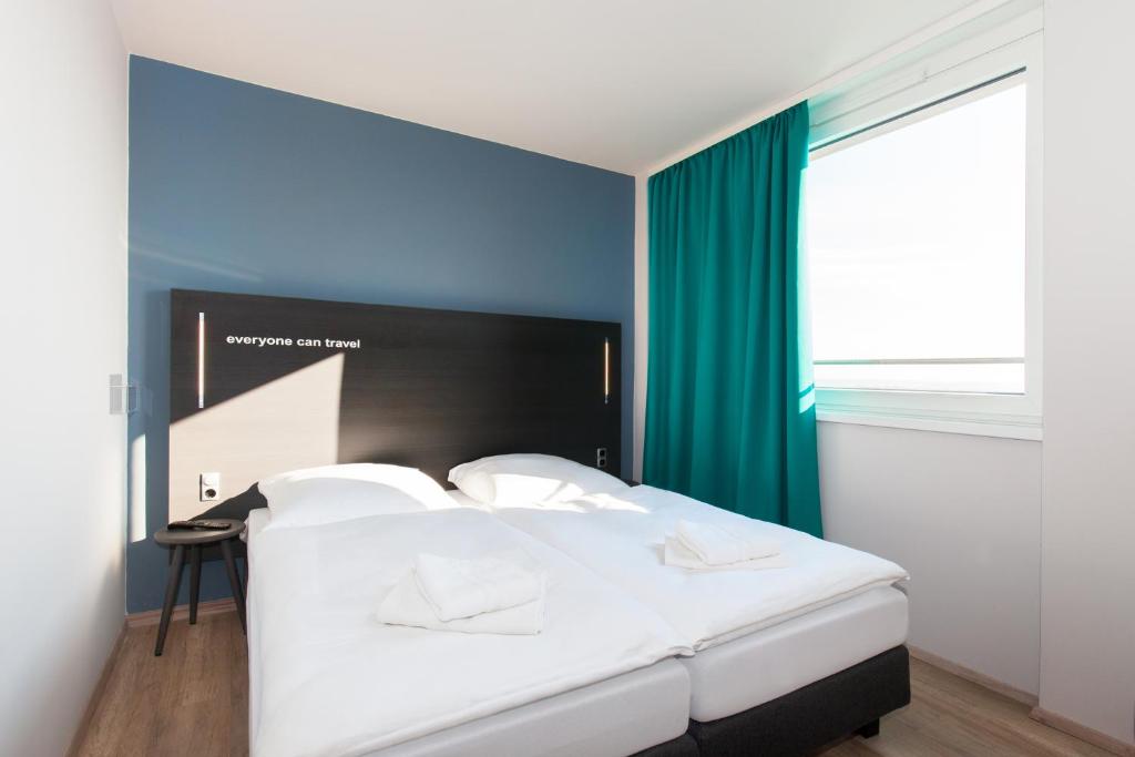 a bedroom with a white bed with a blue wall at a&o Prague Rhea in Prague