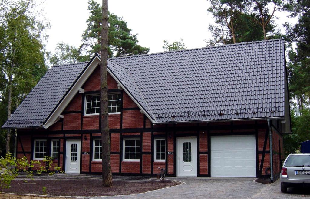 une maison en briques rouges avec un garage blanc dans l'établissement Apartment-Sonnenparadies-Wandlitz, à Wandlitz