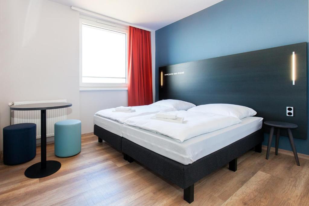 a bedroom with a bed with a black headboard and a table at a&o Prague Rhea in Prague