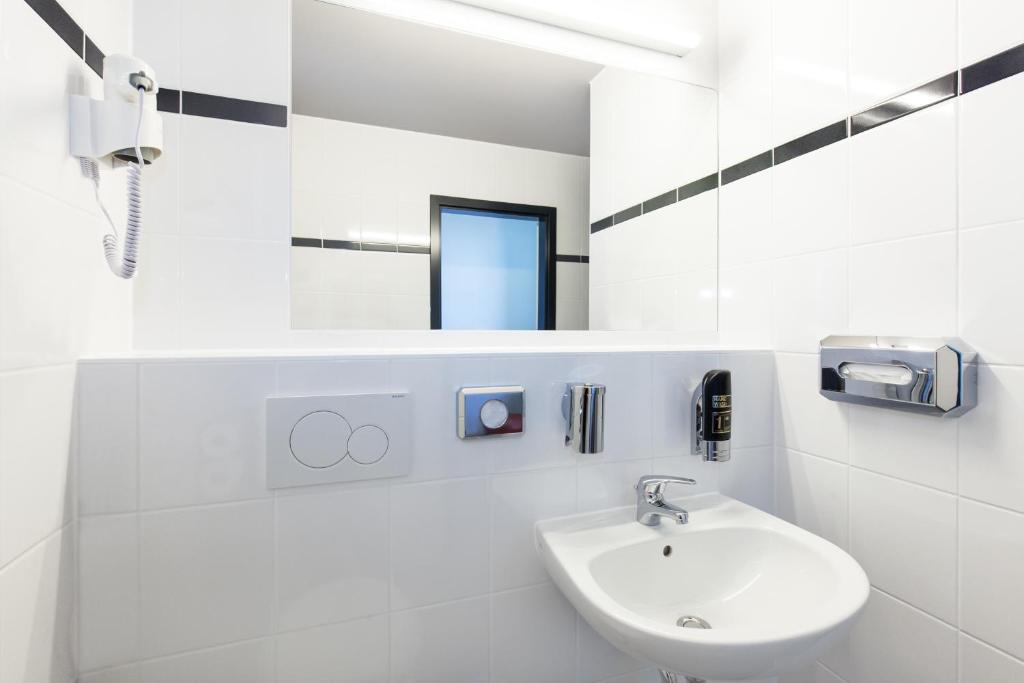 a white bathroom with a sink and a mirror at a&o Prague Rhea in Prague
