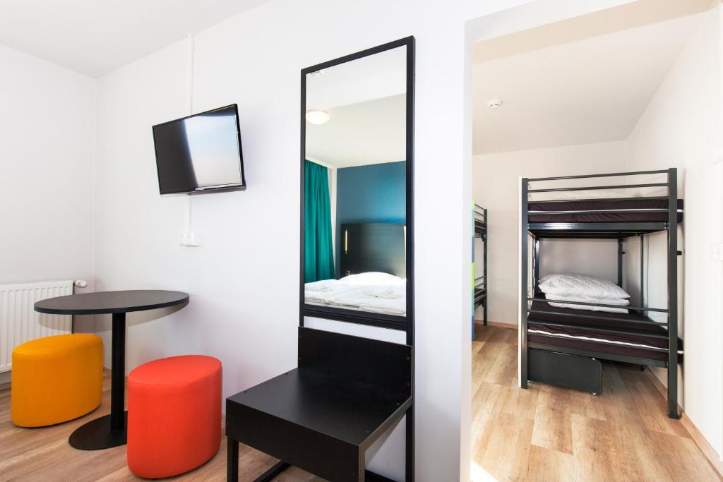 a room with a mirror and a table and a bed at a&o Prague Rhea in Prague